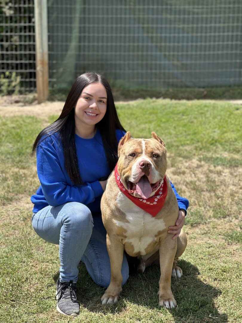 A woman kneeling down next to a dog.